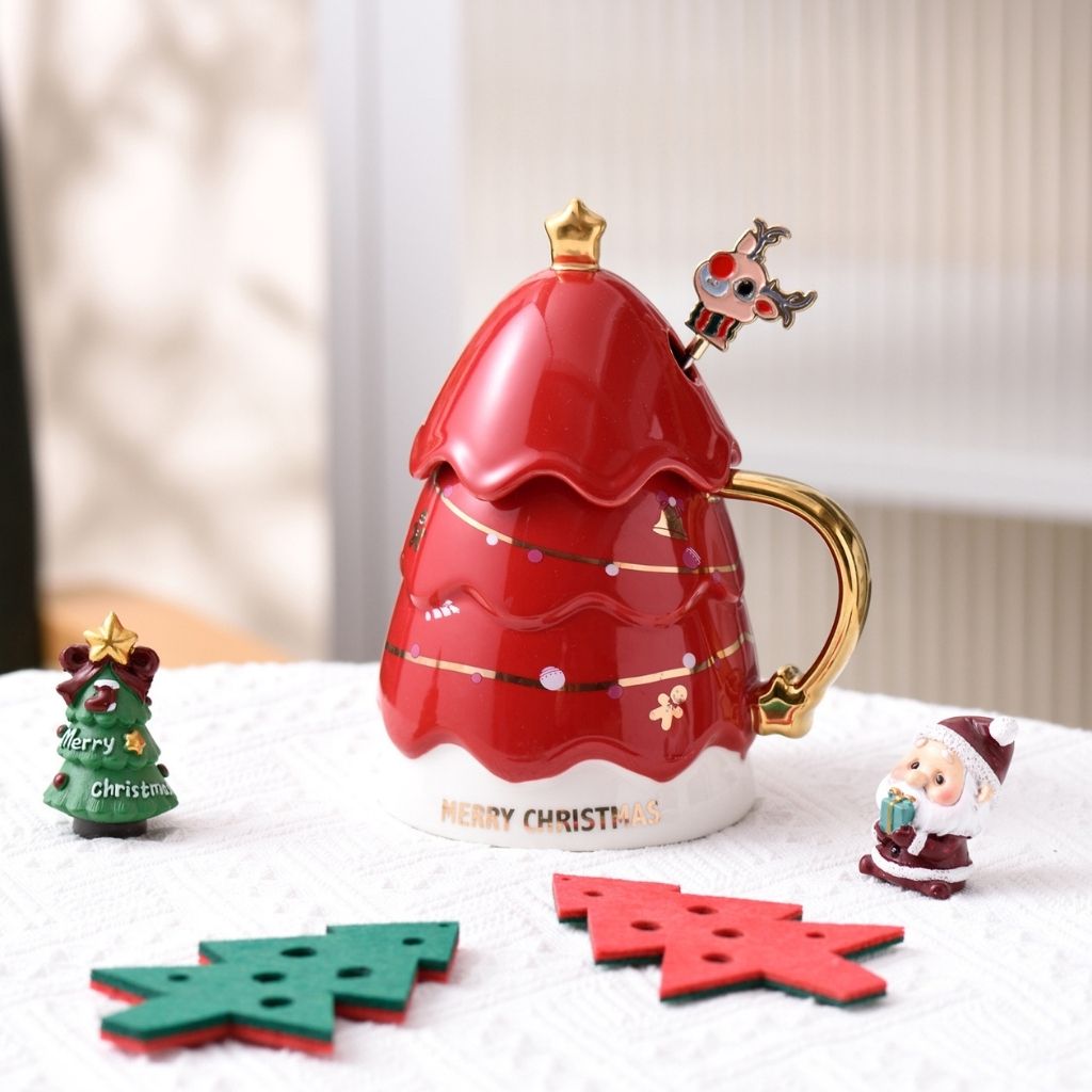 Festive holiday cup with tree design lid next to matching spoon in gift box