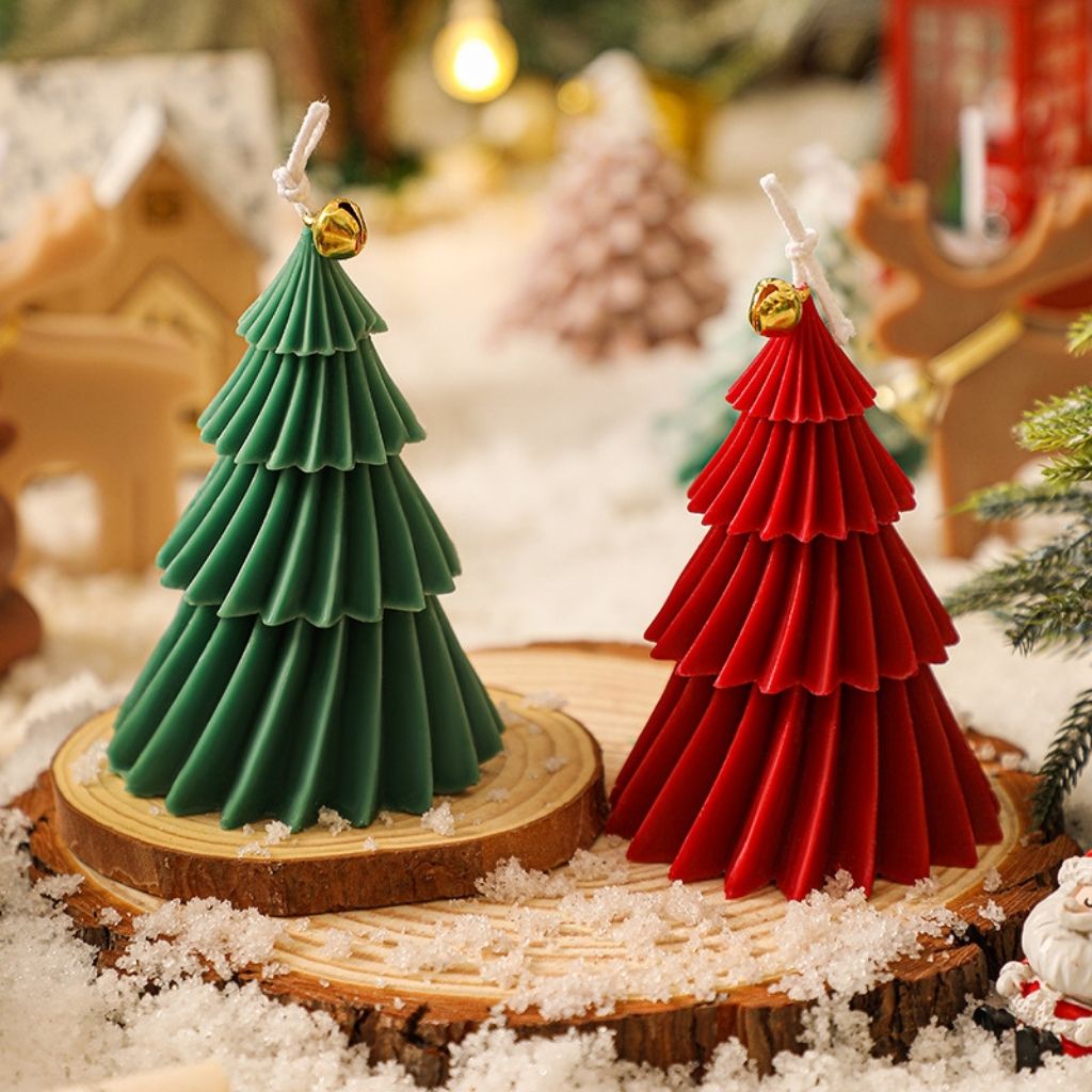 Hand crafted holiday candle with tiered spiral structure and festive bell ornament