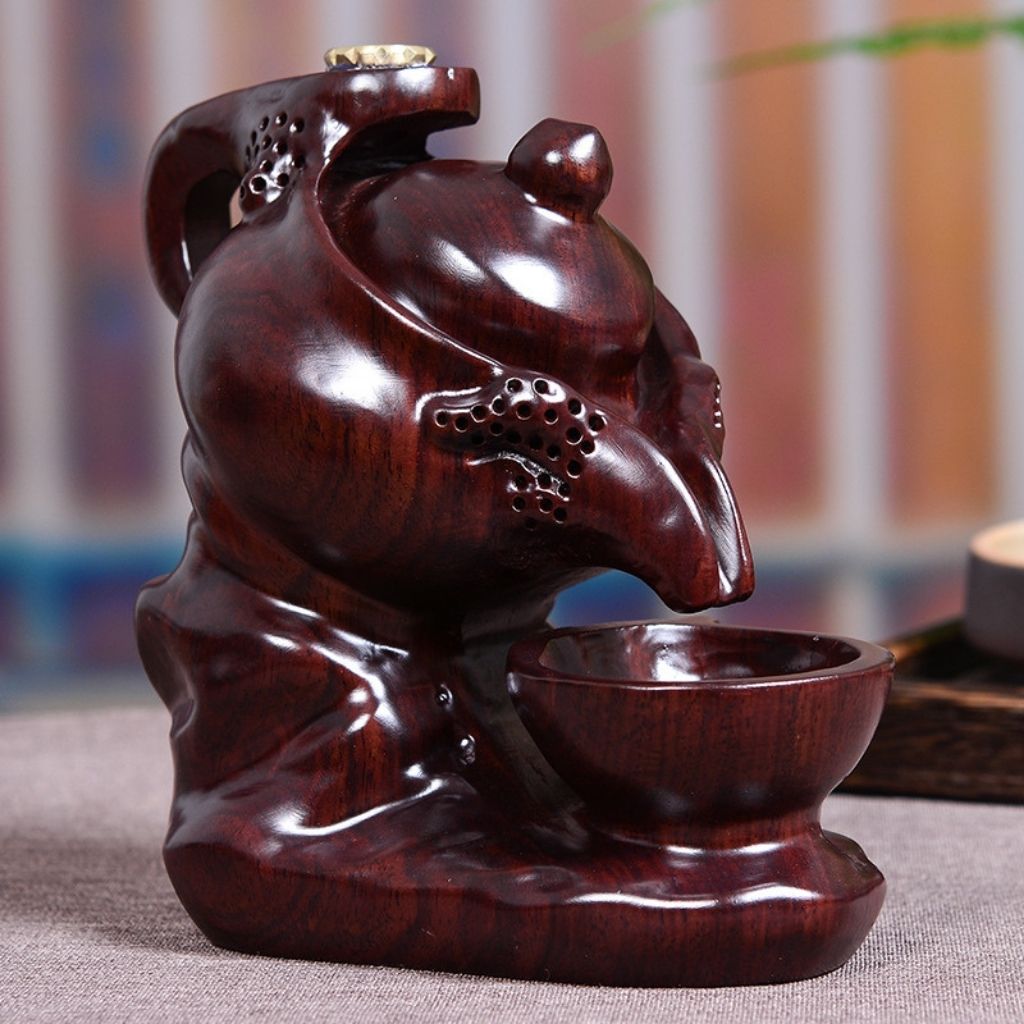 Glossy black ebony wood incense holder with rounded body and curved handle detail