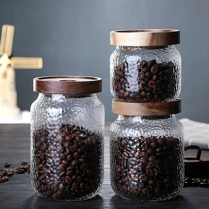 Glass vessel with tight-sealing wooden lid designed for fresh ingredient storage in contemporary kitchens.