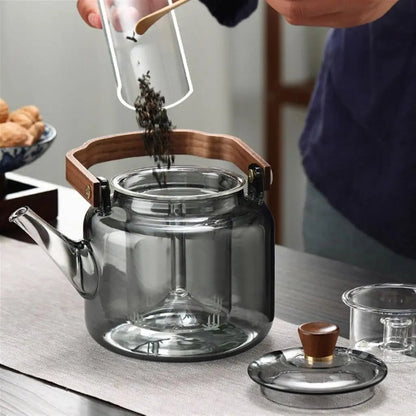 Close-up of premium borosilicate glass teapot showcasing natural ashwood handle and integrated tea infuser