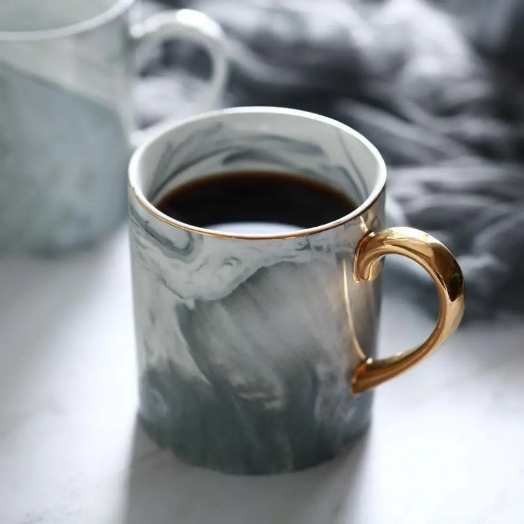 Ceramic marble mug with gold handle featuring gray pink marble pattern for coffee tea serving