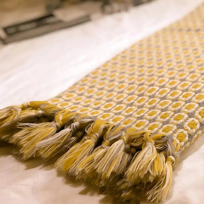 Geometric throw blanket in warm yellow tone featuring Nordic knit construction and tassel trim