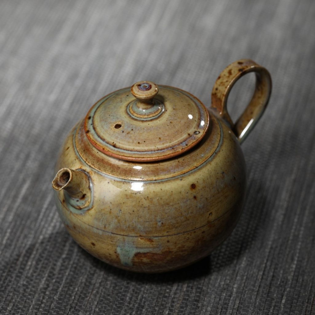 Ceramic teapot with fitted lid and handcrafted glaze pattern in warm tones